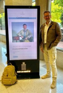 Julio de la Iglesia posa junto al cartel de bienvenida que anuncia su conferencia en Edificio Cuzco IV